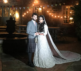 Asian bride and groom embrace outside Fingask Castle at night